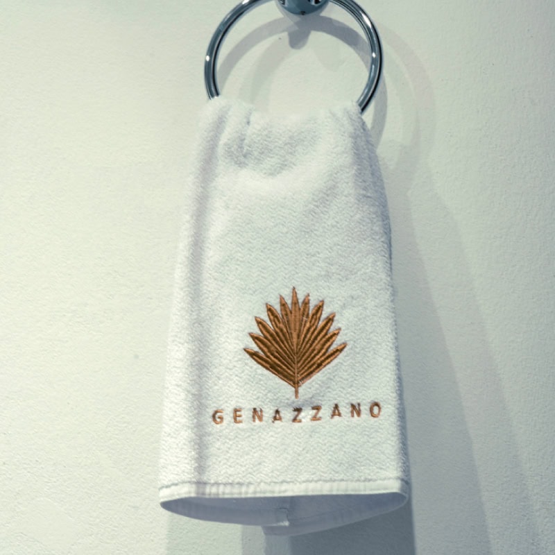 Toalla hotelera blanca con logotipo Gemazzano, ideal para manos y cuerpo en hoteles y spas.