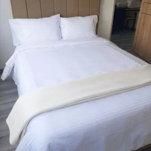 Juego de sábanas blancas de microfibra sateen horizontal en cama de hotel